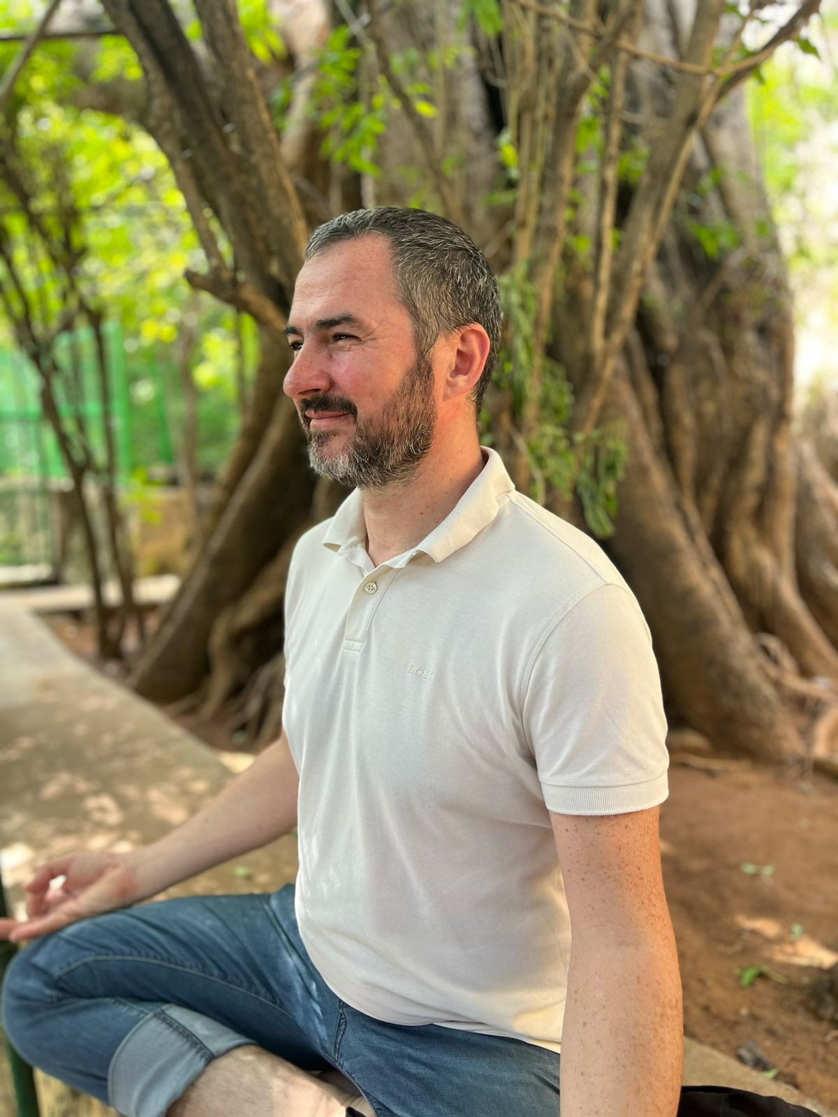 Ivan sitting peacefully in meditation under a large old tree